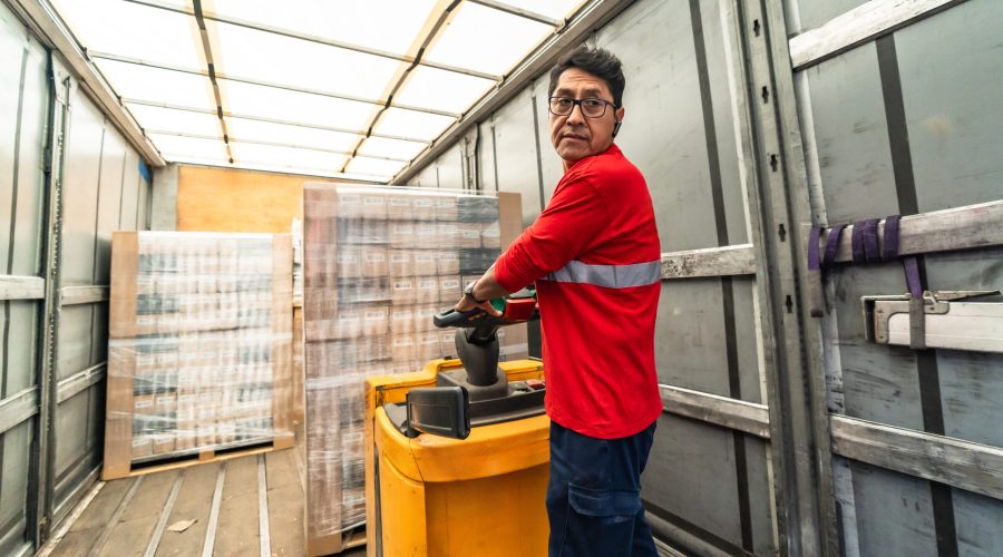 Rear view of a concentrated latin man worker loading a delivery truck in distribution warehouse